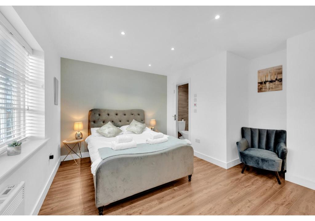 una camera bianca con un letto e una sedia di Classic 2BD Flat in Chelmsford a Chelmsford