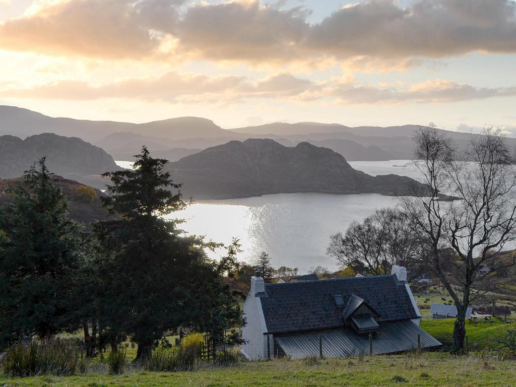 a house on a hill next to a body of water at Eleven Diabaig Cottage in Dibaig