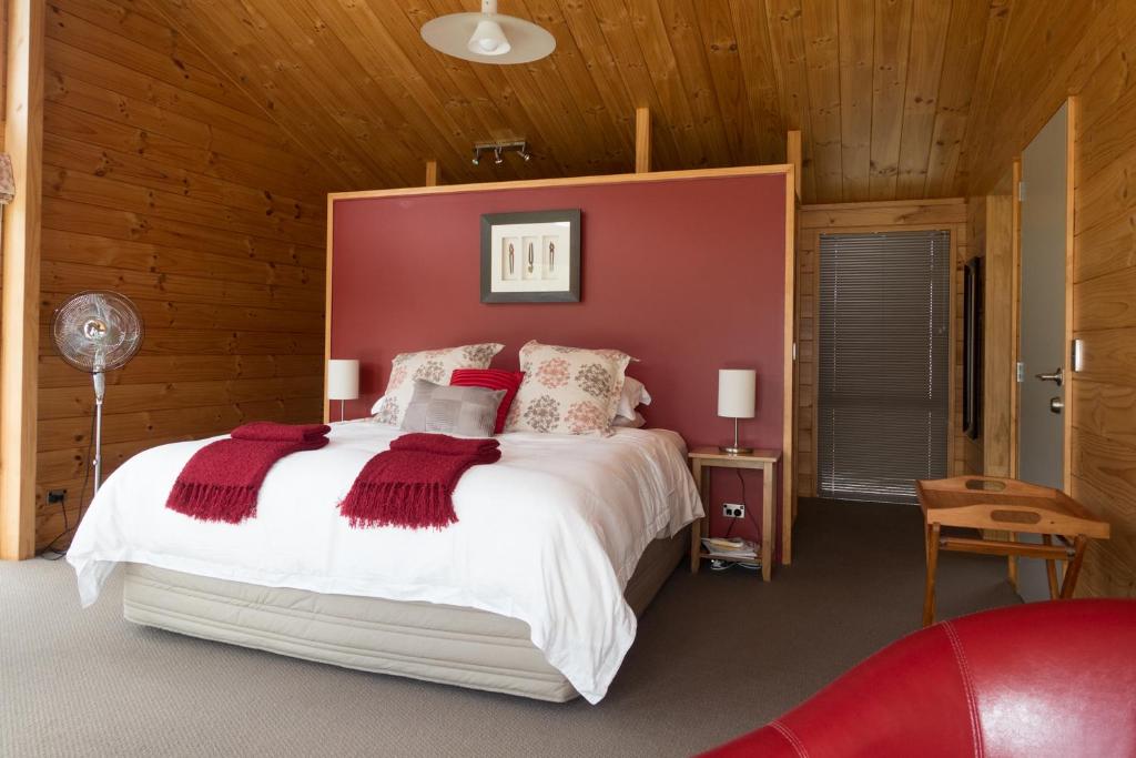 1 dormitorio con 1 cama grande y cabecero rojo en Astelia Lodge, en Horohoro