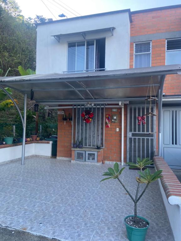 una casa con toldo y un banco frente a ella en Casa en Villa Verde Pereira, en Pereira