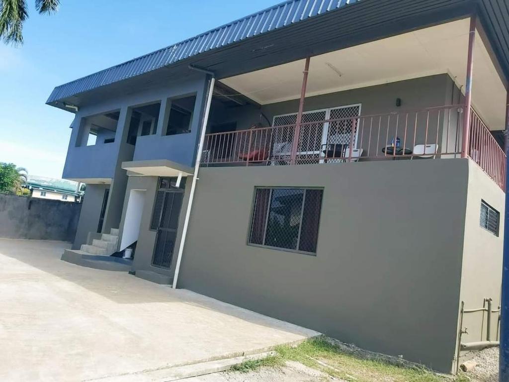 a white house with a balcony on the side of it at Barrett Accommodation Budget Rooms in Suva