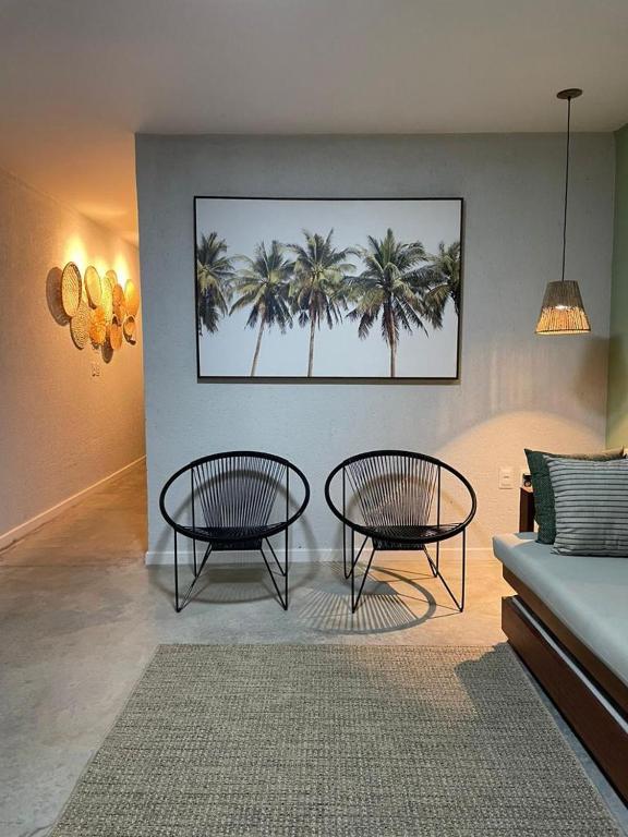 a living room with two tables and palm trees at VILA CORALLI CASA 05 in Passo de Camarajibe