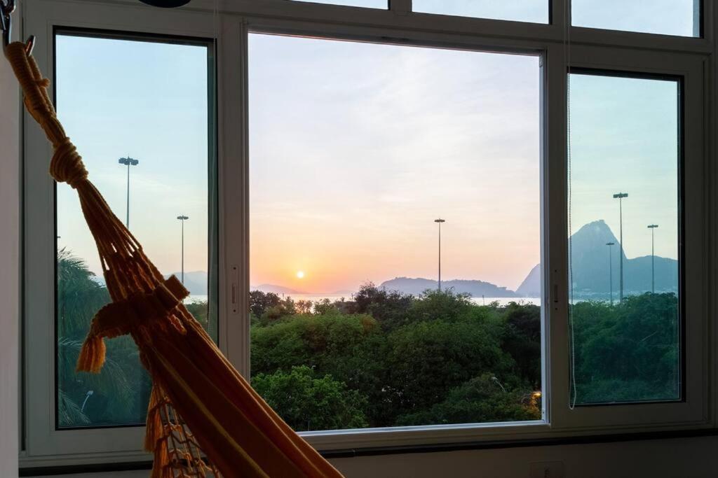 eine Hängematte vor einem Fenster mit Sonnenuntergang in der Unterkunft Kit Rio - vista mais linda do RJ in Rio de Janeiro