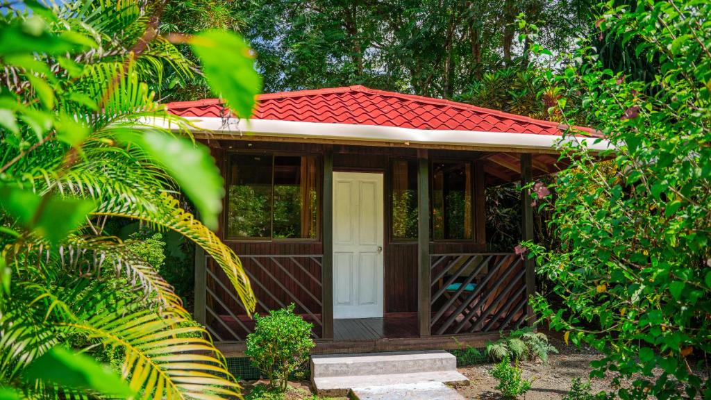 una casa con techo rojo y puerta blanca en Kalea Yard Hotel, en Puerto Jiménez