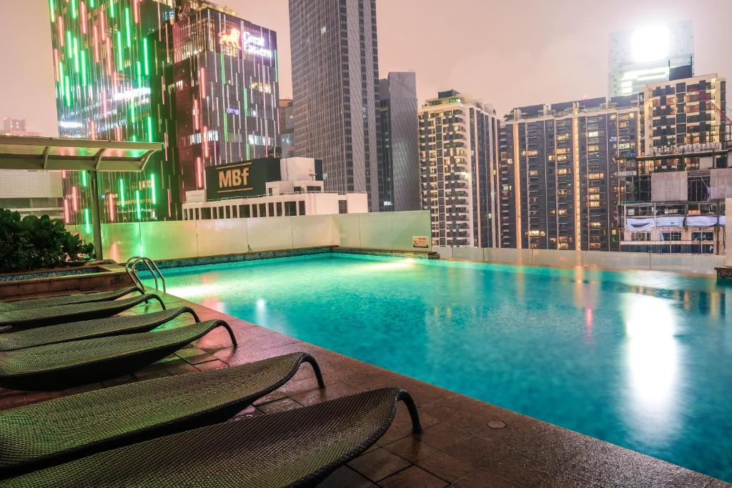 a swimming pool on the roof of a building with chairs at 400m to KLCC Bukit Bintang Pavillion KLCC LRT walking distance in Kuala Lumpur