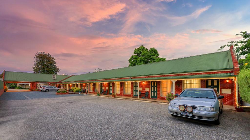 une voiture garée dans un parking en face d'un bâtiment dans l'établissement Elms Motor Inn, à Tumut