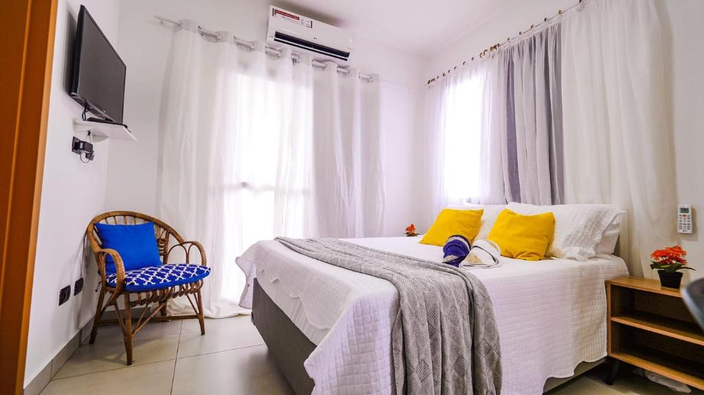 - une chambre avec un lit doté d'oreillers jaunes et bleus dans l'établissement Chalé Amarelo, à Itanhaém