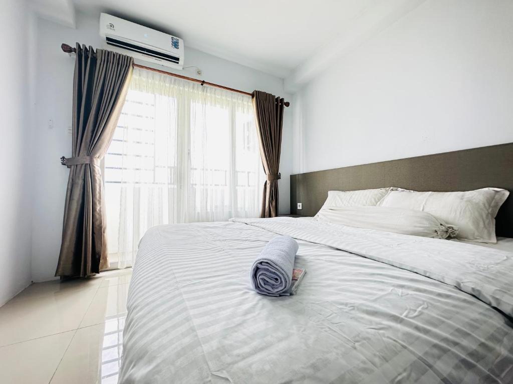 a bed with a towel on it with a window at Super Deluxe Apartment with Skypool Medan in Sunggal