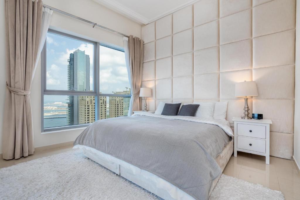 a bedroom with a bed and a large window at Perfect 2BD apartment in the heart of Marina - top spot in Dubai