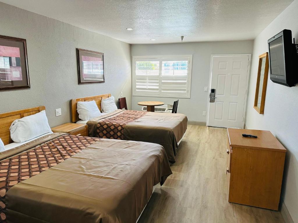 a hotel room with two beds and a flat screen tv at Morgan Hill Inn in Morgan Hill