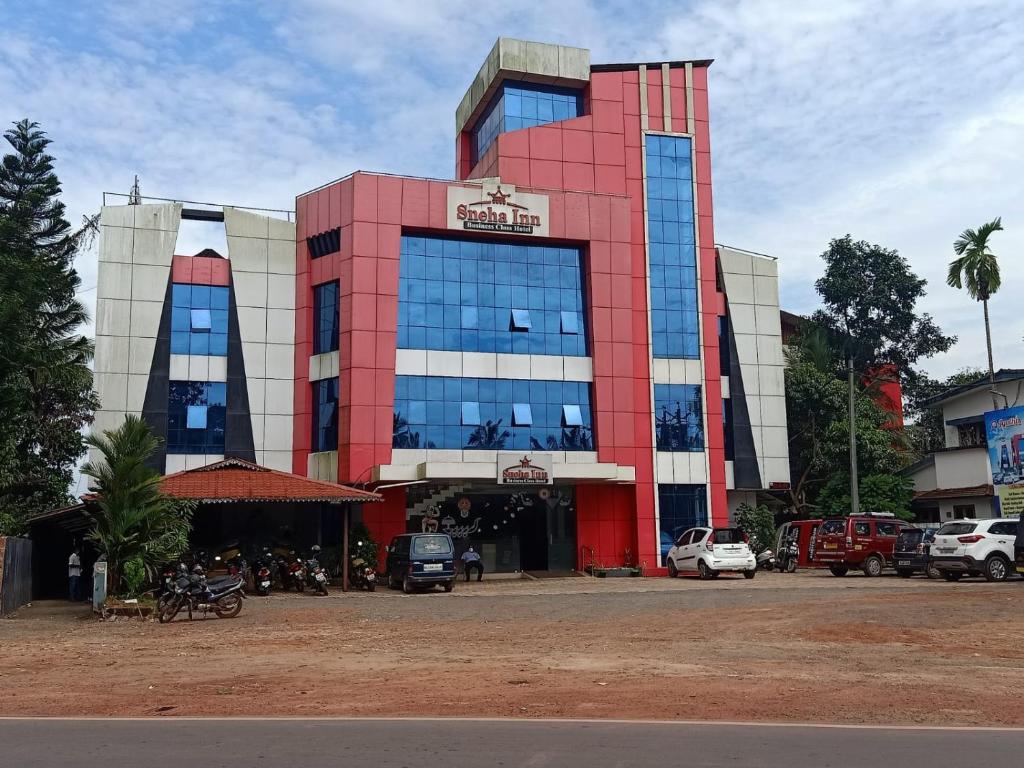 a large building with cars parked in front of it at Sneha Inn in Kannur
