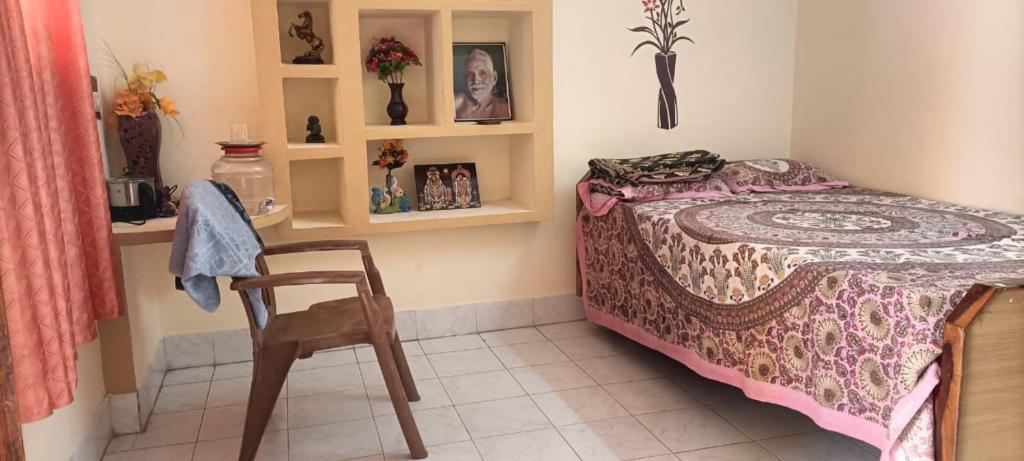 ein kleines Schlafzimmer mit einem Bett und einem Stuhl in der Unterkunft ANBU RAMANA Guest House in Tiruvannāmalai