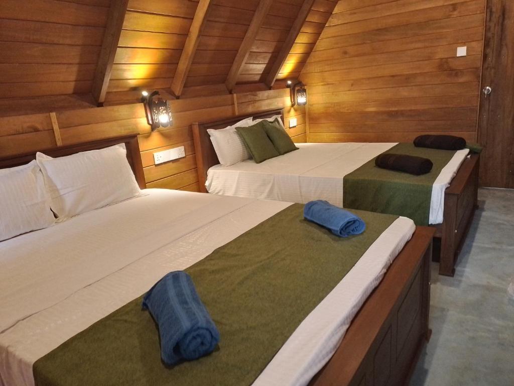 two beds in a room with wooden walls at Habarana New Star Homestay in Habarana