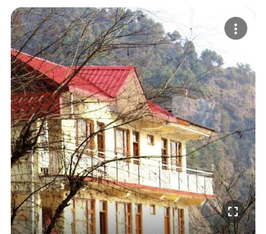 a large white building with a red roof at Hotel Anuj Regency in Dharamshala