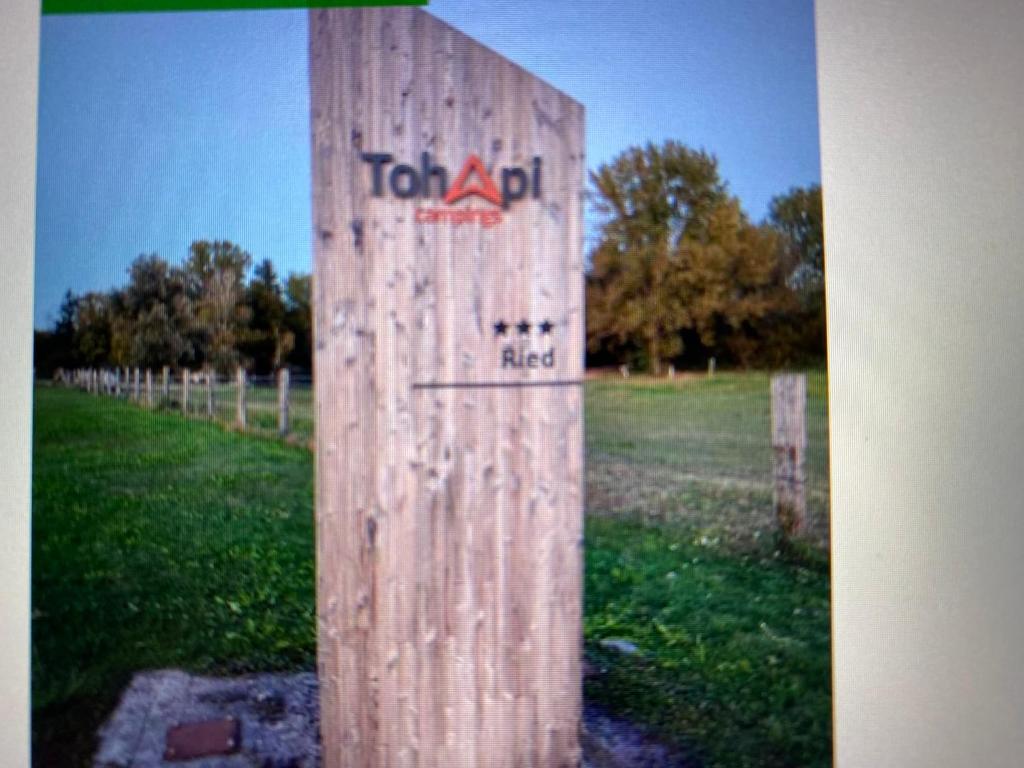 a wooden post with a sign on it in a field at MOBIL HOME Clim BOOFZHEIM 6 PERSONNES 3 CHAMBRES LE RIED 3 ETOILES PROCHE EUROPA PARK in Boofzheim