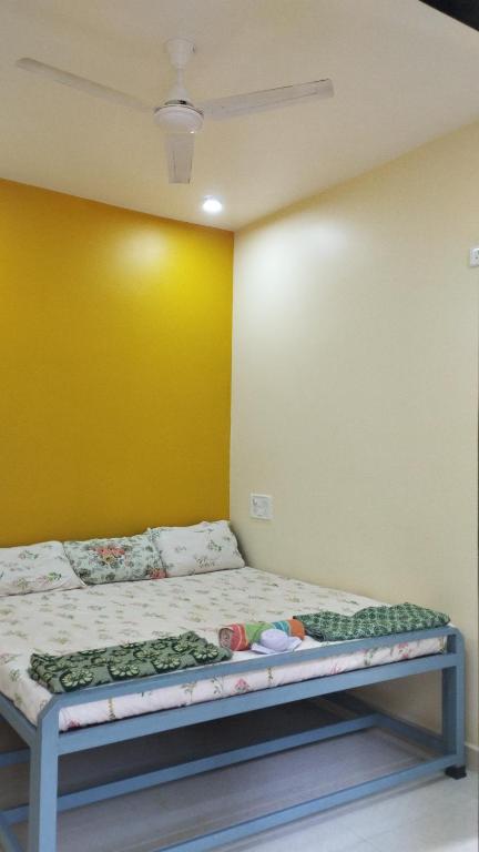 Cama en habitación con pared amarilla en आंगण होम स्टे, en Malvan