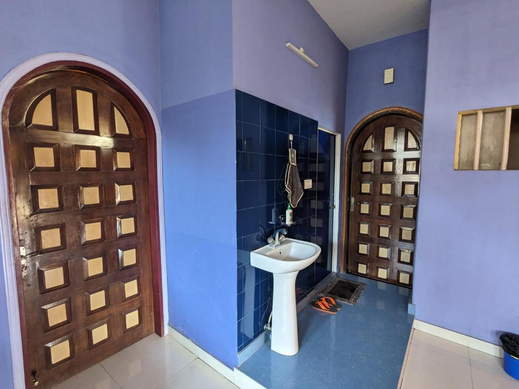 a bathroom with a sink and a wooden door at Saikia Nest the Home-stay in Guwahati