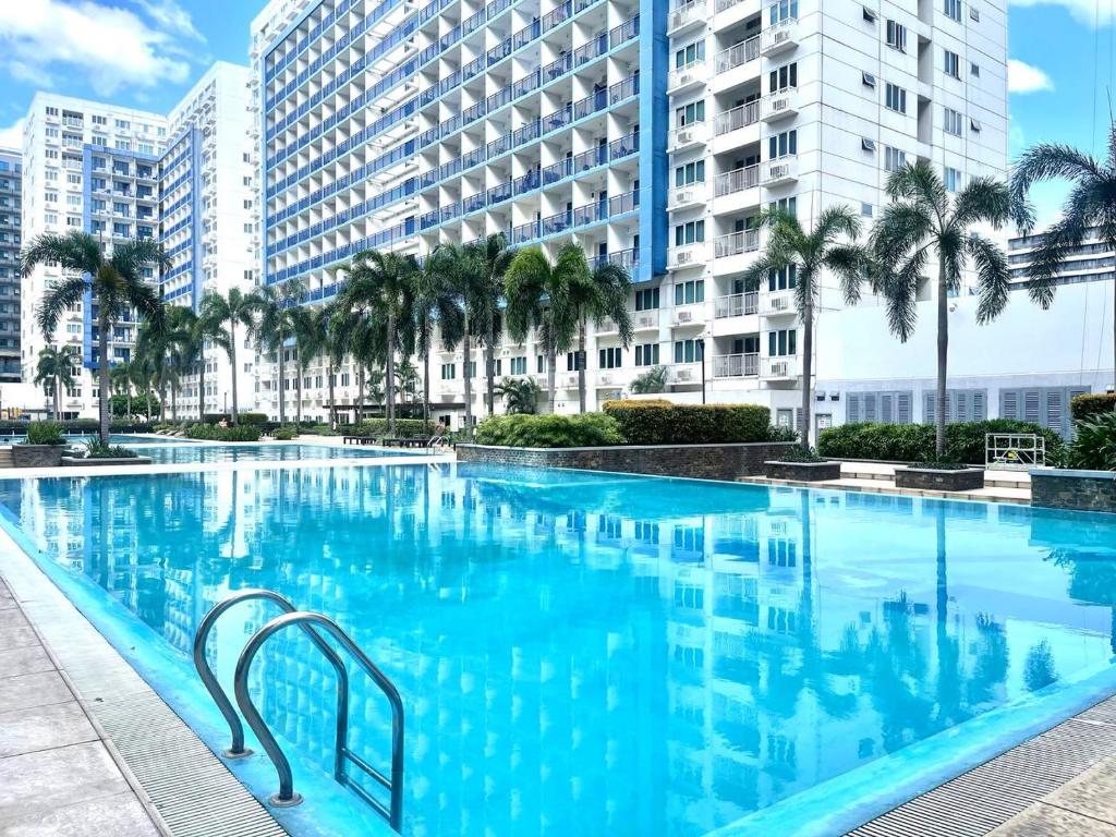 een groot zwembad met palmbomen en gebouwen bij PREMIERE HAVEN at Sea Residences Condominium in Manilla