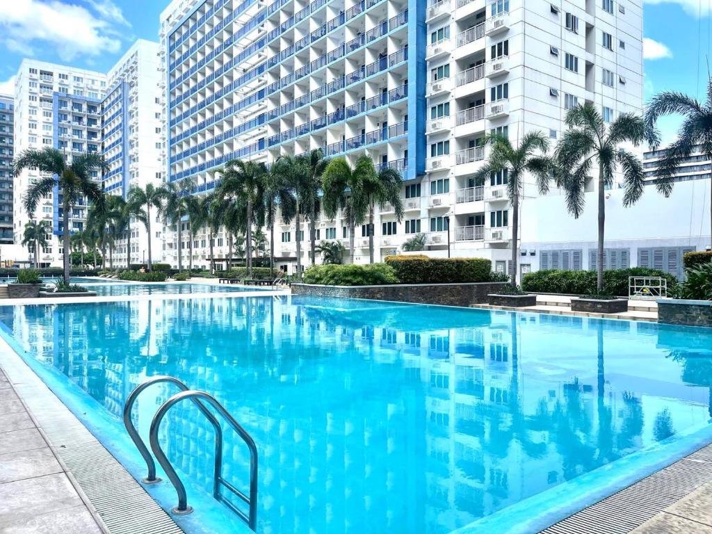 une grande piscine avec des palmiers et des bâtiments dans l'établissement PREMIERE HAVEN at Sea Residences Condominium, à Manille