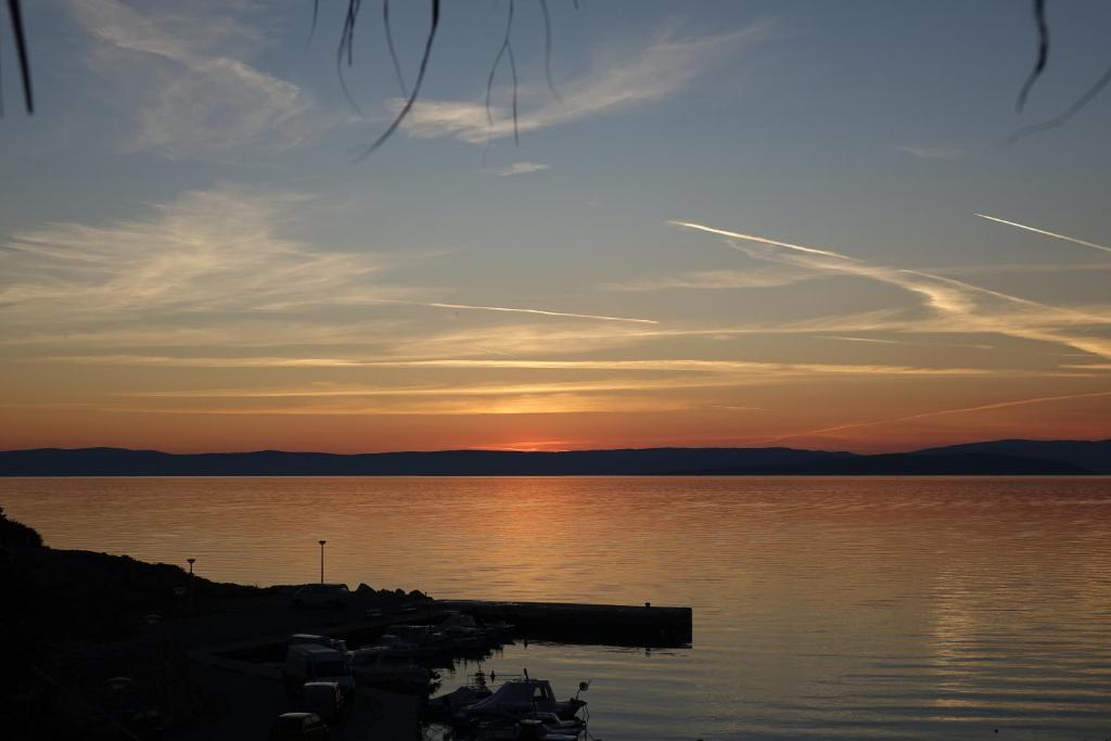 a sunset over a body of water with boats at Eola Leisure Rooms in Stara Baška