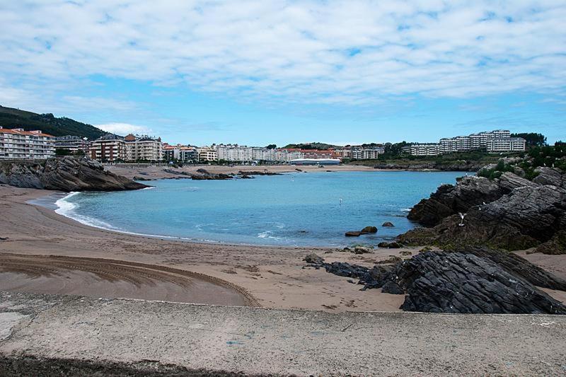 a beach with rocks and buildings in the background at Ático cerca de la playa in Castro-Urdiales