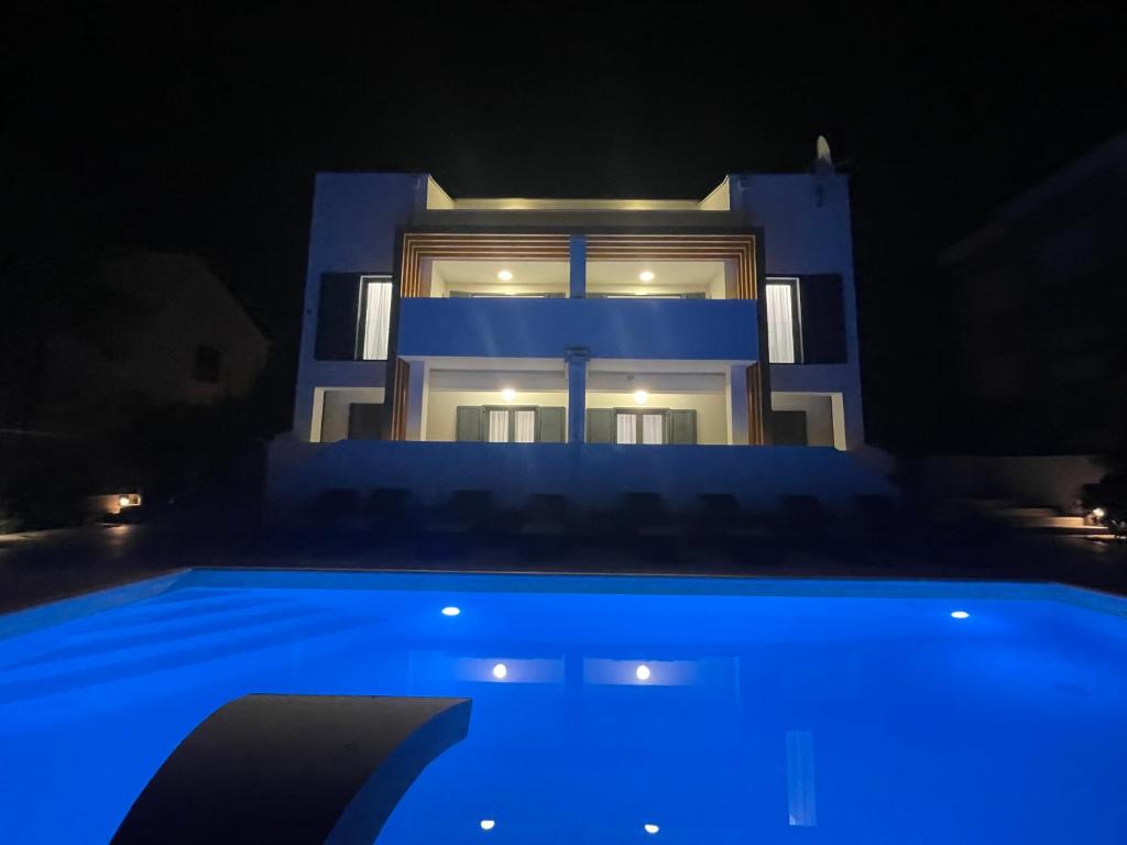 une maison avec une piscine bleue la nuit dans l'établissement Villa Aquamarine Apartments, à Novalja