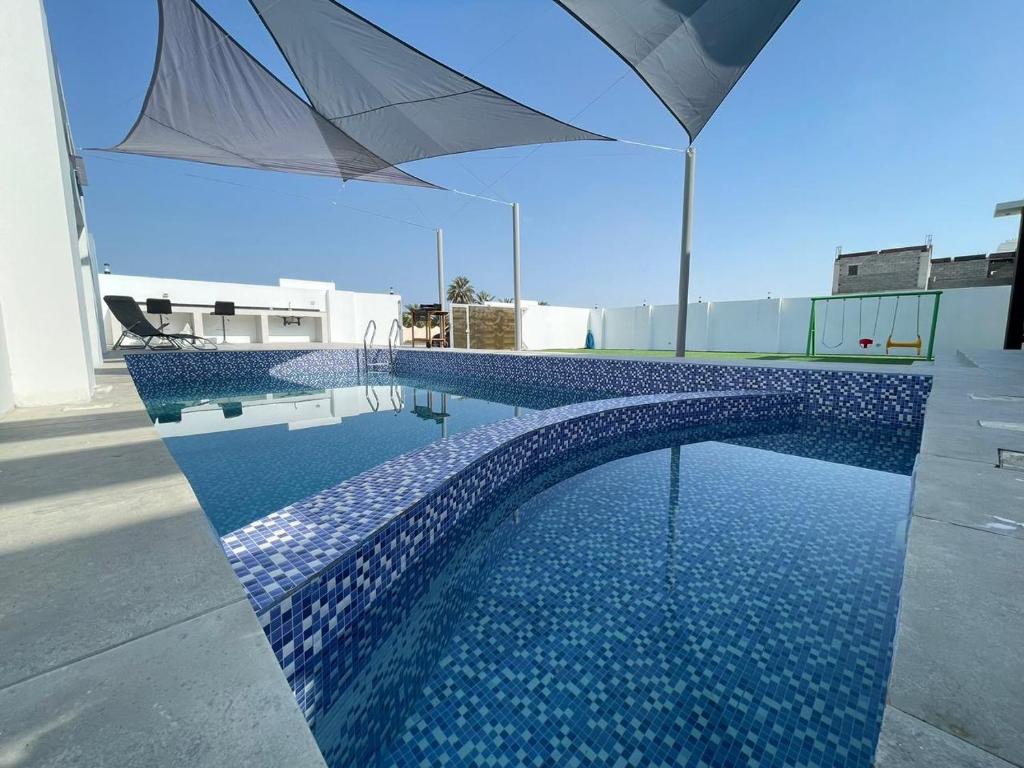 uma piscina com um guarda-sol no topo de um edifício em Bareeq Rest House em Barka