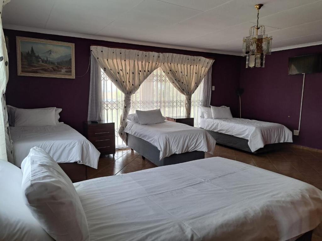 1 dormitorio con 3 camas y pared púrpura en Gae la boroko @legodi's, en Brakpan
