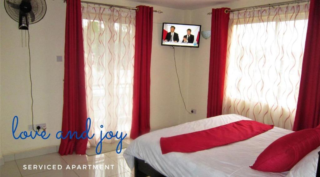 1 dormitorio con cortinas rojas, 1 cama y ventana en Rental Furnished Apartment{ Two Bed Room }, en Kisumu
