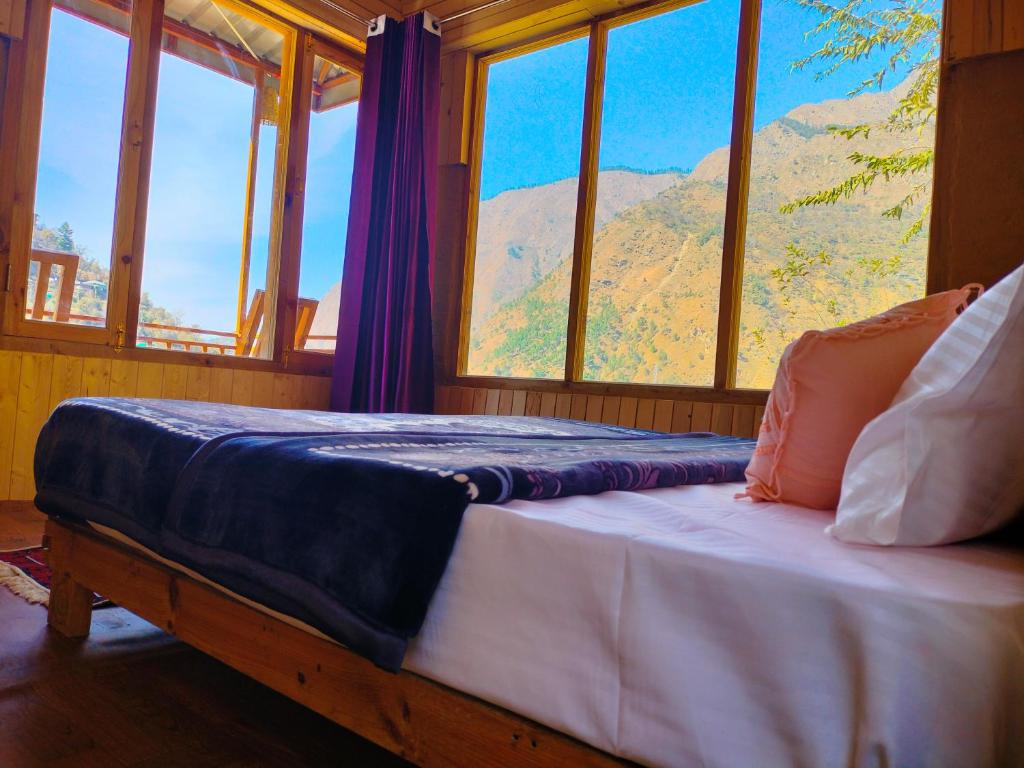 a bedroom with a bed with a view of a mountain at Pyare Cafe Cottages And Tents in Gushaini