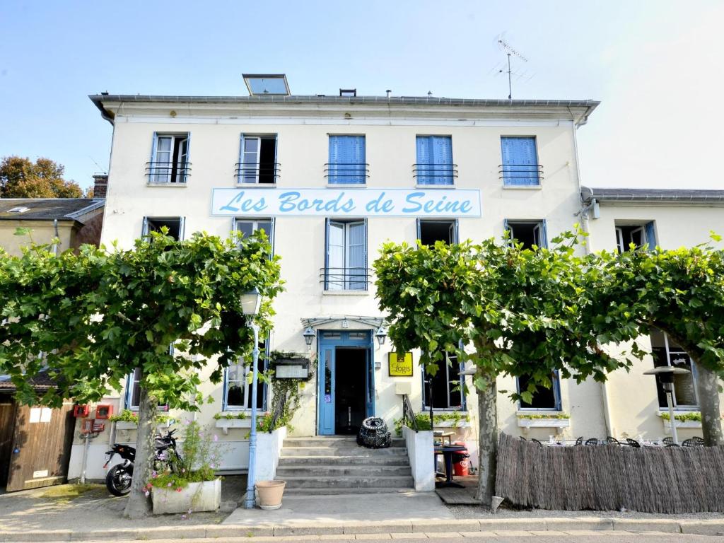 un edificio blanco con un cartel. en LOGIS Hôtel & Restaurant - Les Bords de Seine en La Roche-Guyon