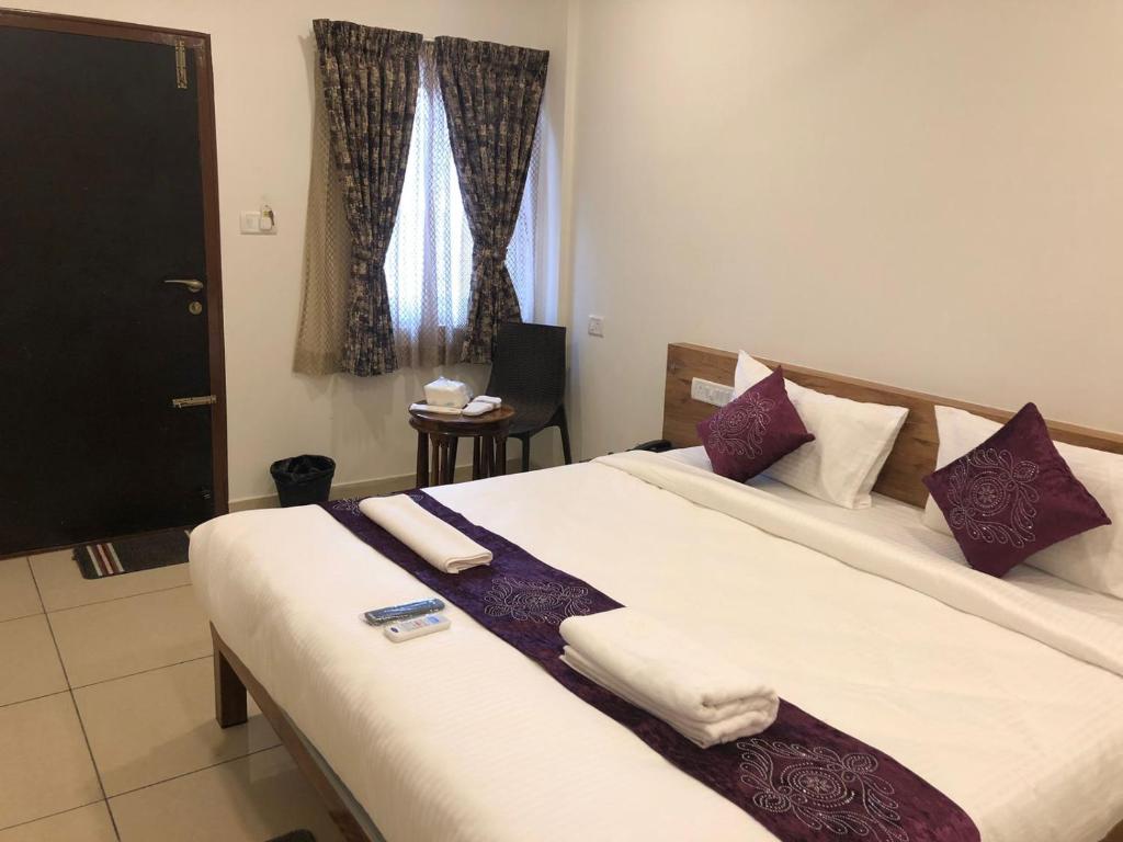 a bedroom with a large bed with purple and white pillows at Hotel Amulya Regency in Bangalore