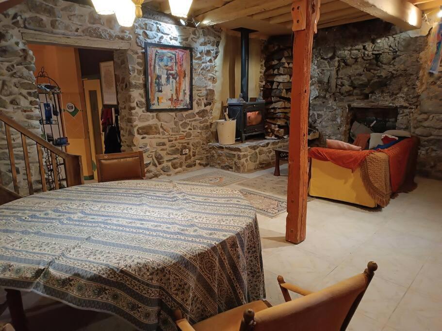 Habitación con mesa y pared de piedra. en Gîte Groupe La Farigoule à Siguer, en Siguer