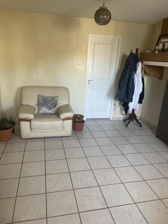 chambre simple proche aéroport في Pusignan: غرفة معيشة مع كرسي وأرضية من البلاط