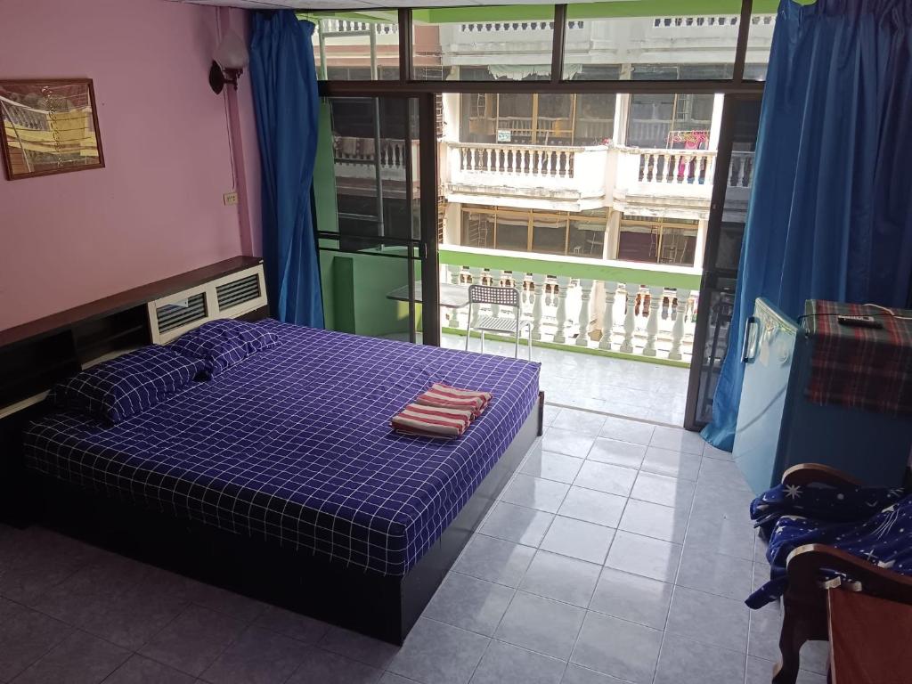 a bedroom with a purple bed and a large window at Yuri Guesthouse in Jomtien Beach