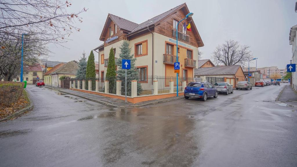 una casa al lado de una calle con coches aparcados en Pension Bavaria, en Brasov
