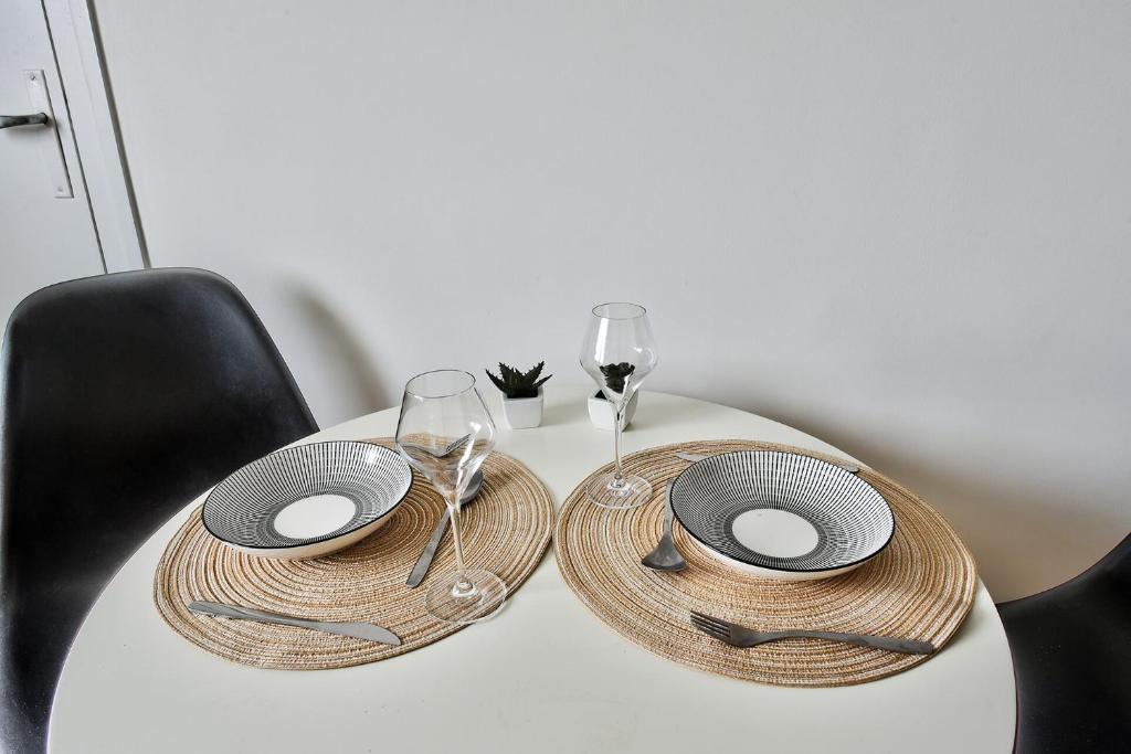 a table with two plates and wine glasses on it at Studio cosy bressan in Bourg-en-Bresse
