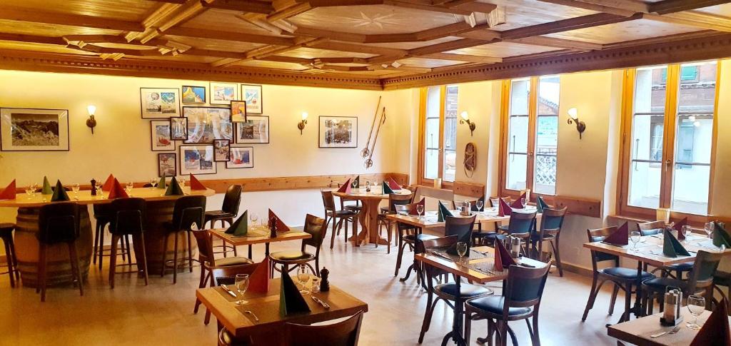 a restaurant with tables and chairs in a room at Hotel de Commune in Gstaad