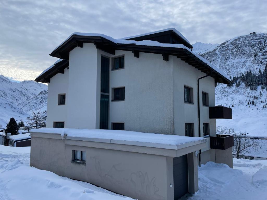 DG Russi Bella Vista في أندرمات: منزل مغطى بالثلج مع جبال في الخلفية