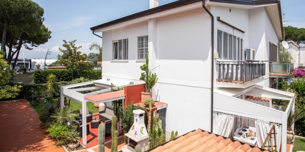 a white house with a balcony with a guitar at Villa Viola - 350 mt from the beach - Outdoor Jacuzzi in Terracina