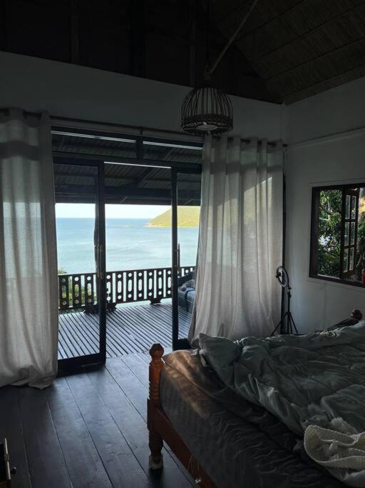 a bedroom with a bed and a view of the ocean at Hidden Viewpoint House in Mae Haad