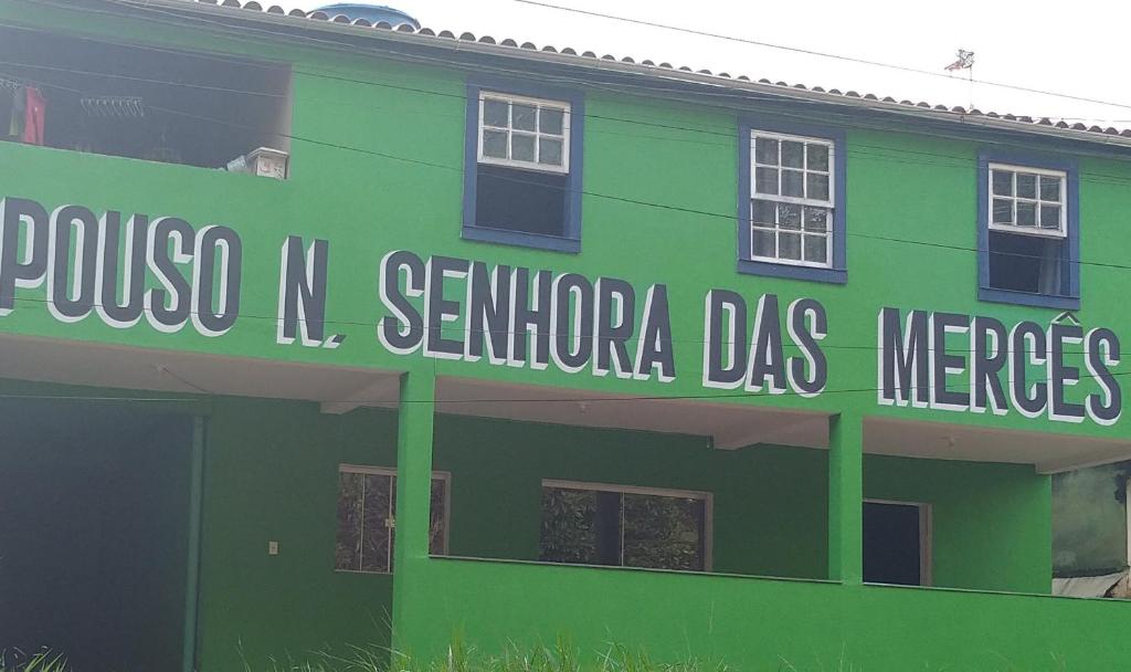 een groen gebouw met een bord aan de zijkant bij Pouso nossa senhora das merces in Tiradentes