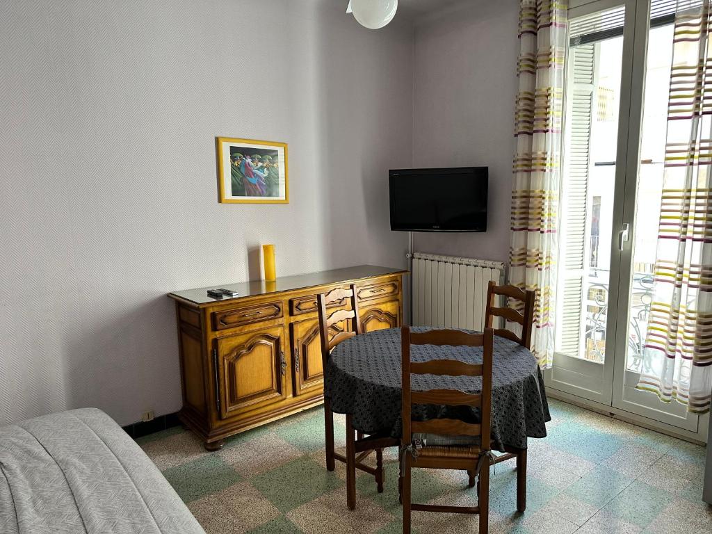 - une chambre avec un bureau, une table et des chaises dans l'établissement APPARTEMENT N°1 LES CLEMATITES, à Menton