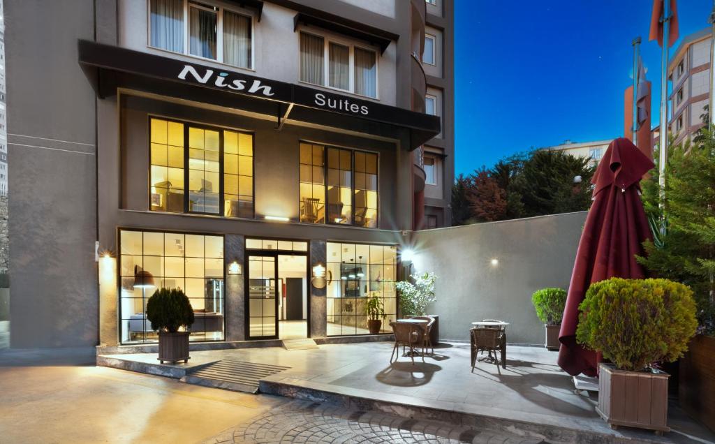 a nissin suites building with tables and chairs and an umbrella at Nish Suites Atasehir in Istanbul