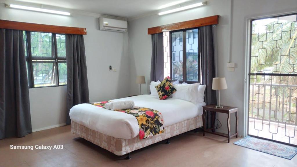 um quarto com uma grande cama branca e janelas em NeemTree Villa- 5 Bedroom House On Its Own em Nadi