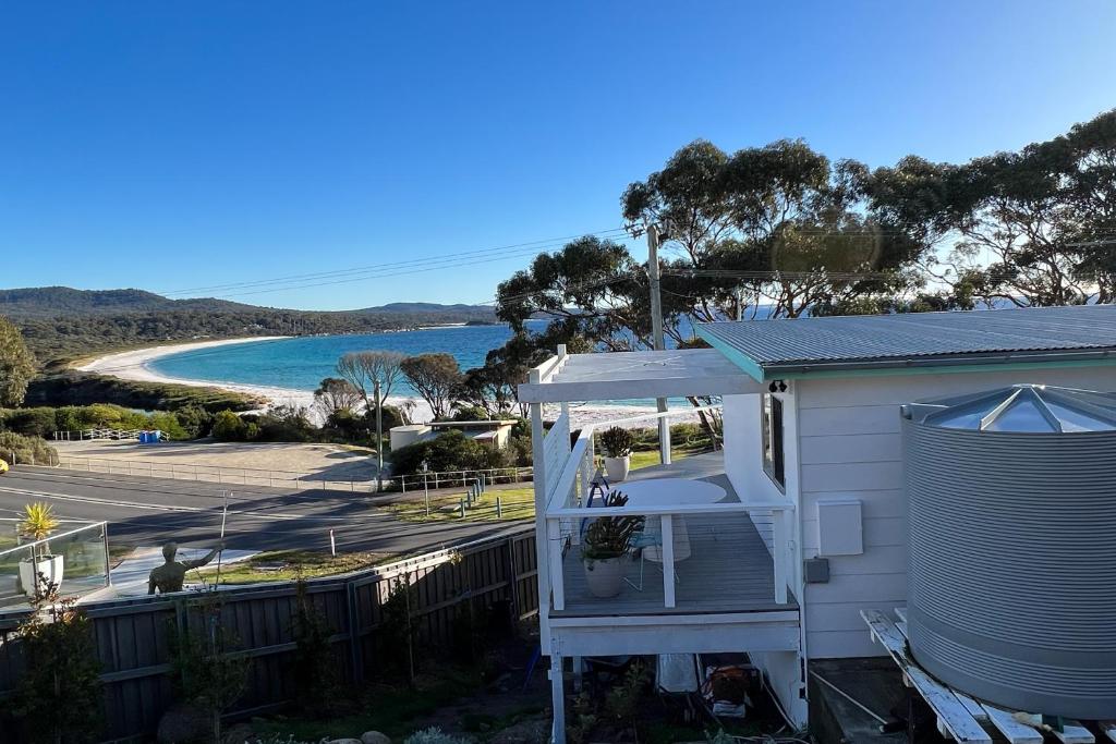 a house with a balcony with a view of a beach at PIPI SHACK - iconic waterfront shack Binalong Bay in Binalong Bay