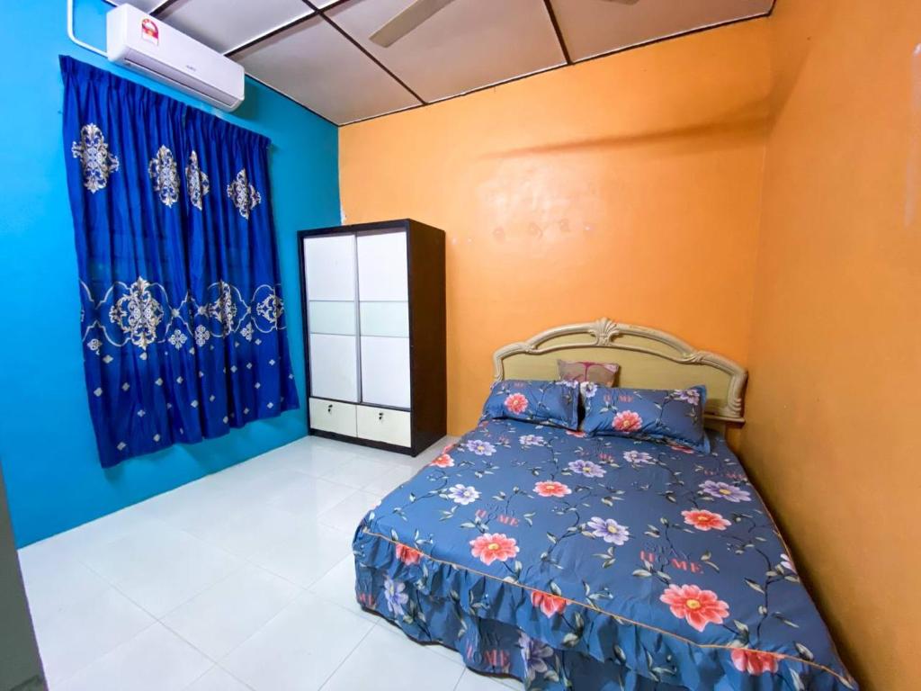 um quarto com uma cama com paredes azuis e laranja em D'JERAI HOMESTAY em Guar Chempedak