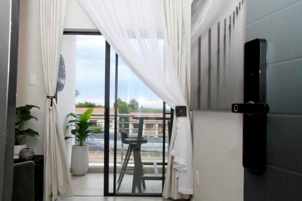 a sliding glass door leading to a balcony with a table at Urbane- By LaSerene -Carlswald in Midrand