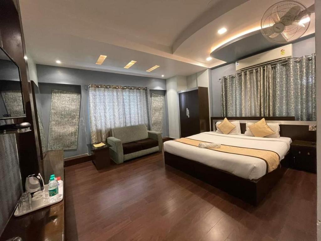 a bedroom with a bed and a chair in a room at Hotel Sundaram Palace in Siliguri