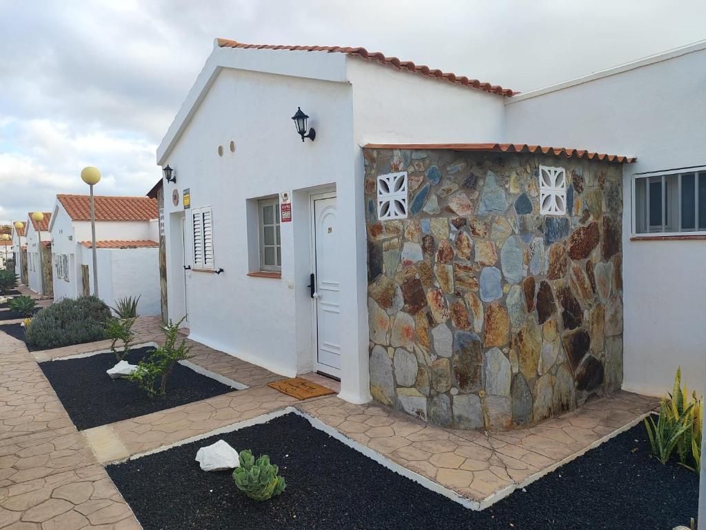 a white house with a stone wall next to it at Casa Yanira in Caleta De Fuste